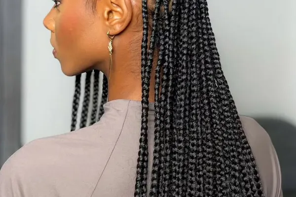 Side view of black cornrow braids finished with patterned clay beads at the ends