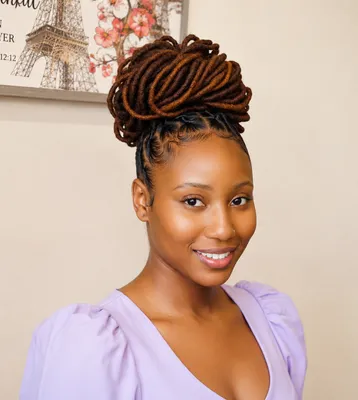 Woman with auburn dreadlocks styled into a high twisted bun