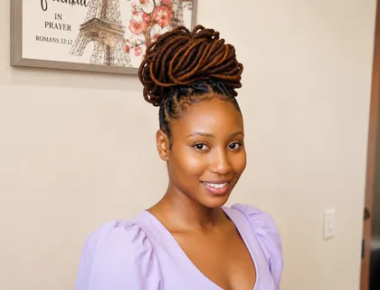Woman with auburn dreadlocks styled into a high twisted bun