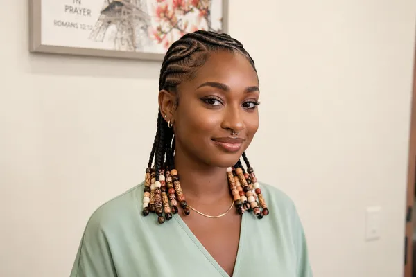 Woman with small knotless braids finished in wooden beads, worn back from her face