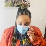 Cornrows swept back into a braided ponytail with gold highlights