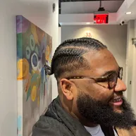 Men's cornrows into a braided ponytail with faded sides