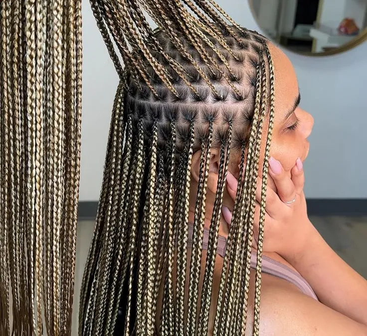 Close-up of blonde-highlighted knotless braids parted in a cornrow pattern at the scalp