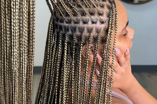 Close-up of blonde-highlighted knotless braids parted in a cornrow pattern at the scalp